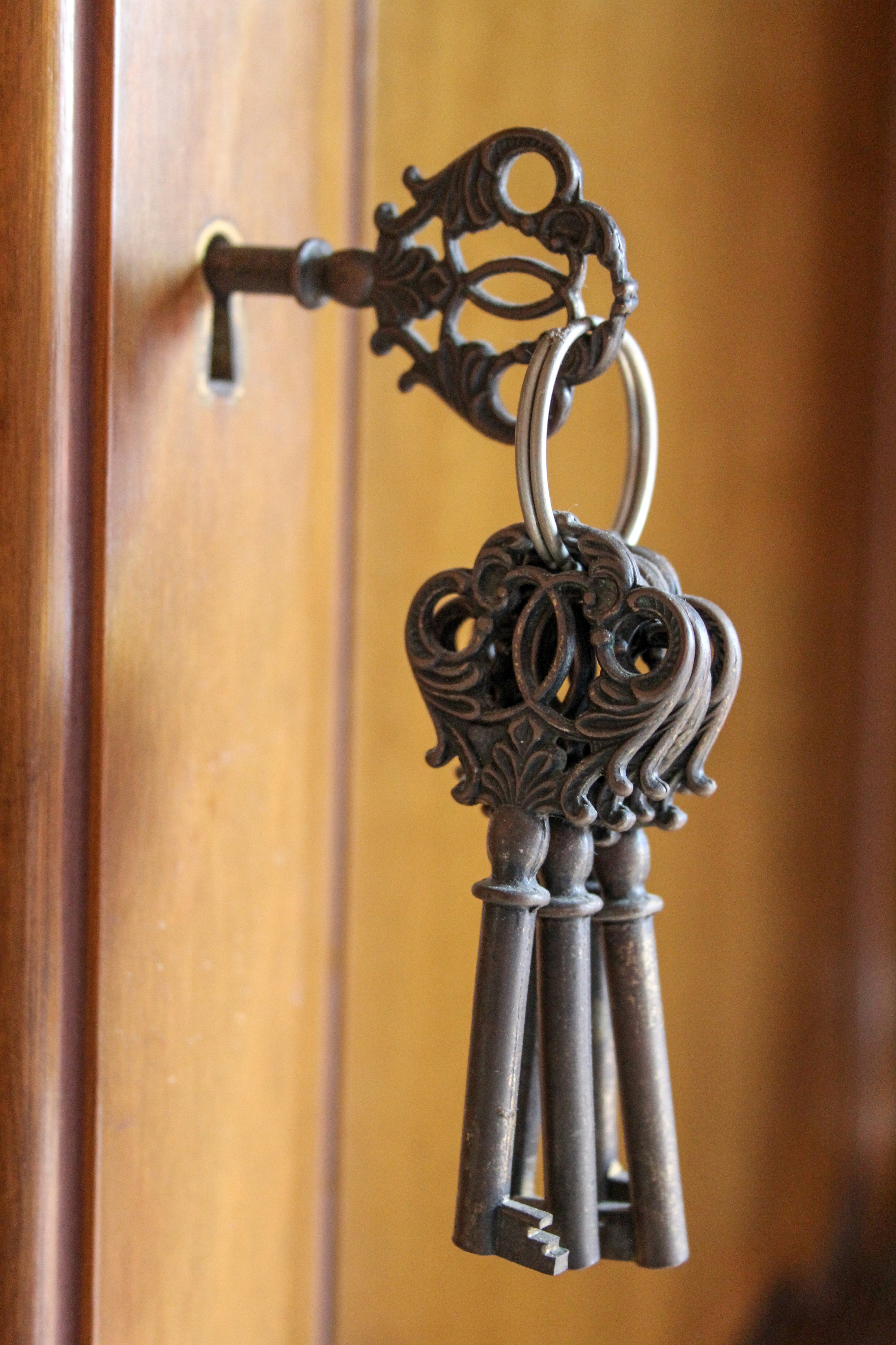 Ornate antique keys hanging from a wooden cabinet
